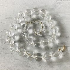 We love the look of this vintage clear lucite (acrylic) round beads statement necklace! Each bead is 5/8" or 16mm in diameter. The necklace can be worn from 17" to 20" long, depending on where the hook is clasped along the wired wrap bead chain. The clasp is gold plated, and the necklace is unsigned. It is in excellent condition, a really fun statement necklace. Adjustable Clear Necklace, Clear Faceted Round Beaded Necklaces, Vintage Clear Round Necklace, Clear Single Strand Crystal Necklace With Round Beads, Clear Crystal Single Strand Necklace With Round Beads, Clear Crystal Necklace With Single Strand Of Round Beads, Vintage Clear Round Bead Necklaces, Clear Glass Round Bead Necklaces, Clear Glass Round Beads Necklaces