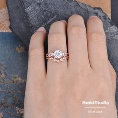 a woman's hand with a diamond ring on her left hand and a stone background