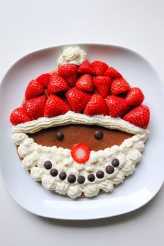 a white plate topped with a cake covered in strawberries