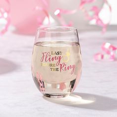 a glass filled with liquid sitting on top of a table next to pink and white balloons