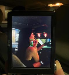 a person holding up a cell phone to take a photo in the back seat of a car