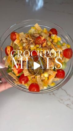 a person holding a glass bowl filled with corn, tomatoes and other vegetables that reads crockpot meals