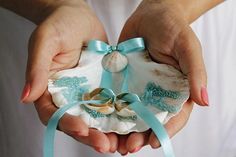 two hands holding seashells with ribbons around them