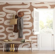 an entryway with a bench, coat rack and hat hanging on the wall next to it