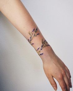 a woman's arm with flowers on it and the wrist is shown in purple