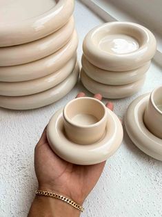 a hand holding a stack of white bowls