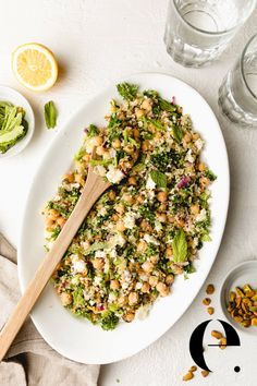 a white plate topped with broccoli and chickpeas next to two glasses of water