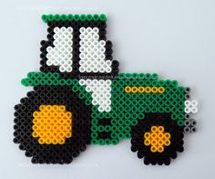 a green and white toy truck made out of perler beads on a white background