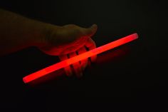 a person is holding two glowing sticks in their hand, one red and the other black