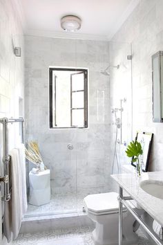 a bathroom with a toilet, sink and shower in it's stall area next to a window