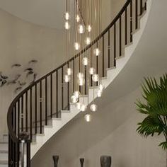 an elegant staircase with chandelier and potted plant