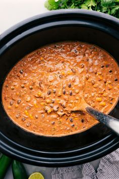 a black crock pot filled with chili and beans, garnished with cilantro