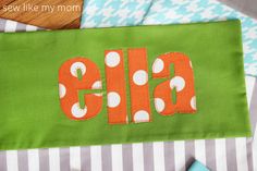 an orange and white polka dot monogrammed name on a green fabric with stripes