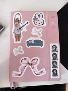 a pink notebook covered in stickers and pictures