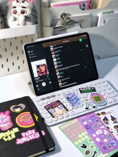 an open laptop computer sitting on top of a desk next to a notebook and various stickers