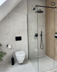 a white toilet sitting next to a walk in shower under a skylight on top of a tiled floor