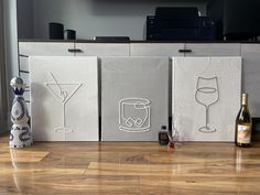 three canvass with wine glasses and a bottle on the floor in front of a flat screen tv