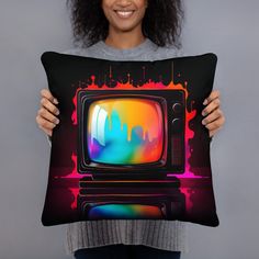 a woman holding up a pillow with an old tv on it in front of her