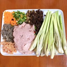 a white plate topped with asparagus, meat and seasoning next to other foods