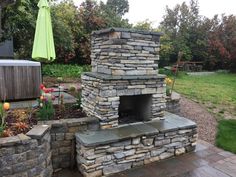 an outdoor fireplace in the middle of a garden