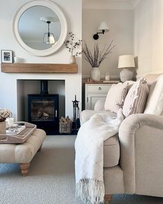 a living room filled with furniture and a fire place under a mirror on the wall