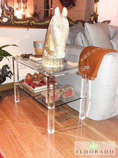 a glass table with a buddha statue sitting on top of it next to a couch