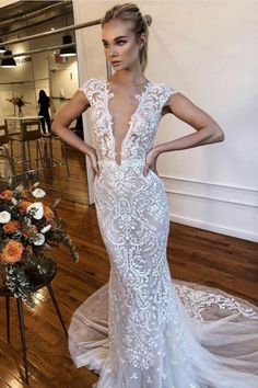 a woman in a white wedding dress standing on a wooden floor with her hands on her hips