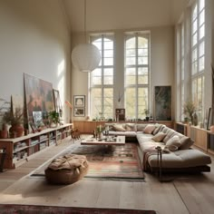 a living room filled with lots of furniture next to large windows and bookshelves