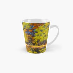 a tall mug with an image of trees in the background and water on the side