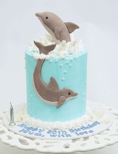 a blue and white cake with two dolphins on it