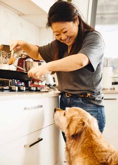 a woman and her dog are cooking in the kitchen