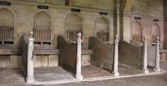 several wooden benches lined up next to each other in a room with stone flooring