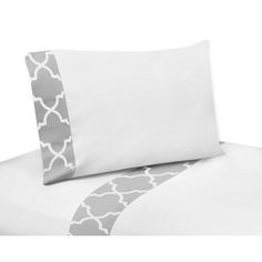 a bed with white and grey sheets and pillow cases on top of each other,