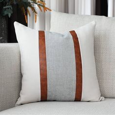 a close up of a pillow on a couch with a plant in the back ground