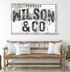 a wooden bench sitting in front of a white wall with a sign that says wilson and co on it