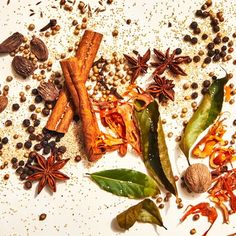 an assortment of spices and herbs on a white surface