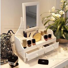 a white vanity with drawers, mirror and cosmetics on it next to a potted plant