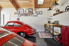 two red cars parked in a garage next to each other on the floor and some pictures on the wall