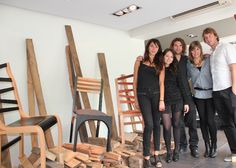 a group of people standing next to each other in front of stacks of wooden chairs