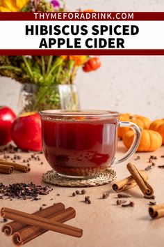 a cup of apple cider with cinnamon sticks and apples in the background text reads hibiscus spiced apple cider