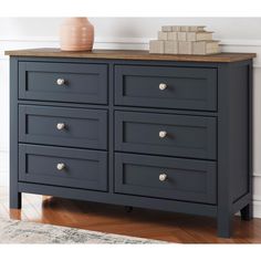 a black dresser with drawers and a vase on top