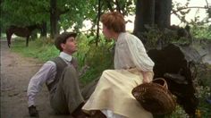 a man sitting on the ground next to a woman in a white dress and brown hat