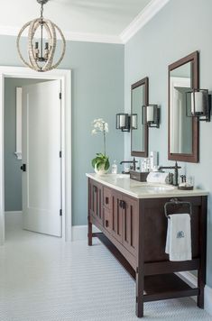 a bathroom with two sinks, mirrors and a chandelier hanging from the ceiling