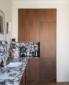 a kitchen with marble counter tops and wooden cabinets in the back drop off area, along with wood flooring