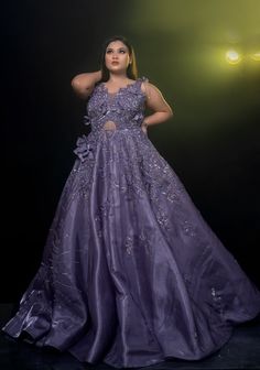 a woman in a long purple dress posing for a photo with her hands on her head