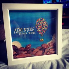 there is a picture frame with coins and a hot air balloon in the sky that says adventure is out there