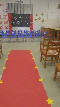 a red carpet with yellow stars on it in front of a row of wooden chairs