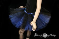 "This adult tutu skirt is handmade from around 35 yards of 12\" long soft smooth Bridal tulle. We put a layer of black tulle over two layers of Royal blue. Then All is tightly machine gathered, tripled, serged and sewn to a black fabric covered elastic waistband for extra durability. (we no longer carry the blue wave fabric as shown). Our tutus are fully sewn, never tied. They are machine washable and dryer safe! This tutu is made 12\" long around mid thigh. This tutu is extra poofy! This skirt Fitted Halloween Party Petticoat, Stretch Petticoat For Halloween Costumes, Halloween Stretch Tulle Petticoat, Stretch Tulle Petticoat For Halloween, Fitted Blue Tulle Petticoat, Blue Fitted Tulle Petticoat, Stretch Tulle Tutu Dress For Costume Party, Fitted Tutu Dress With Attached Cancan For Costume Party, Blue Fitted Tutu Dress For Costume