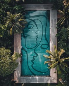 an aerial view of a woman's face in the water surrounded by palm trees