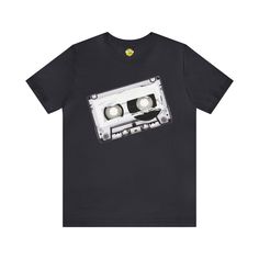 Step back in time to the golden era of music with our "Retro Cassette Tape" Short Sleeve T-Shirt – a blast from the past that echoes the iconic tunes of the 80s and the nostalgia of analog audio. Design Details: Our shirt proudly showcases a meticulously designed retro cassette tape, capturing the essence of an era when mixtapes were carefully curated, and the rewind button was a musical adventure. The graphic design celebrates the enduring appeal of vintage music and transports you to a time when music was as much about the experience as it was about the sounds. Material & Fit: Crafted from soft, premium cotton fabric, this short-sleeve tee provides unparalleled comfort and breathability. The relaxed fit ensures an easy-going style, making it a versatile choice for everyday wear, whether Rewind Button, Retro Cassette, 80s Nostalgia, Audio Design, Blast From The Past, 80s Music, Cassette Tape, Vintage Music, Music Lover